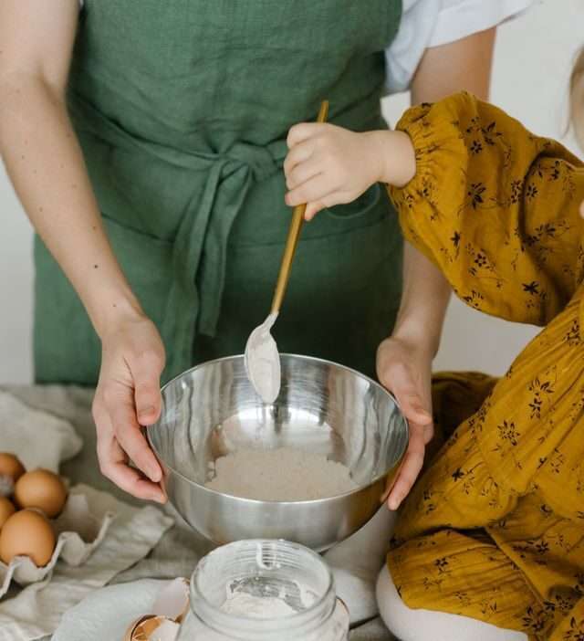 mamma che cucina con figli per insegnarli l'educazione alimentare