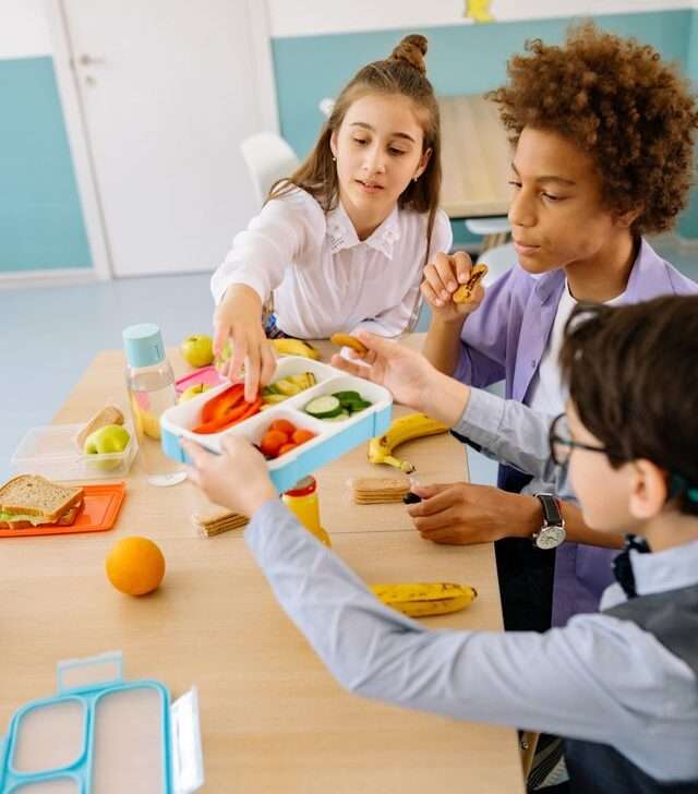 Ragazzi e ragazze che mangiano per illustrare i principi di un'alimentazione sana per adolescenti